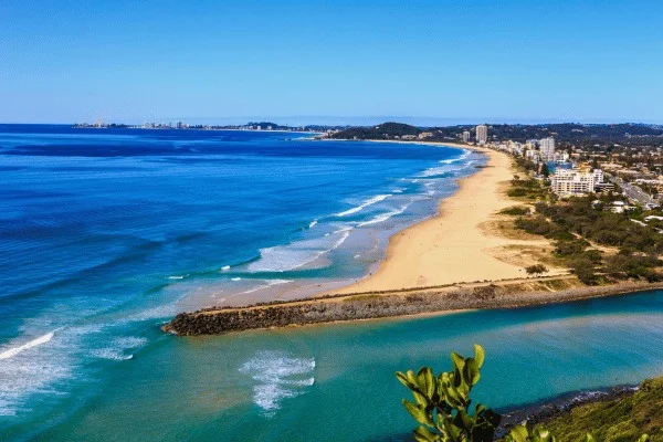 Una amplia vista de la costa muestra playas, barrios urbanizados y un curso de agua dentro del mismo paisaje.