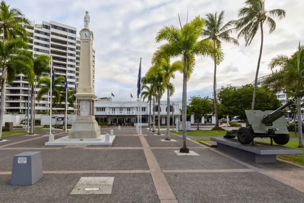 Palms, open paving and surrounding buildings create different conditions of shade around a Cairns memorial.