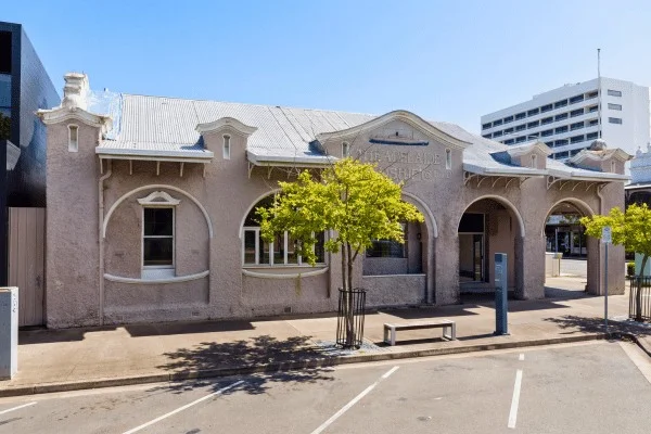 An older Cairns building preserves a different scale from the larger development behind it.