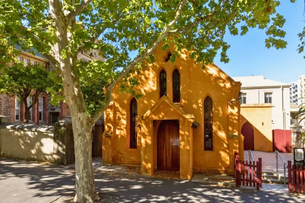 Une petite église et un grand arbre créent un espace intime au cœur de la ville.
