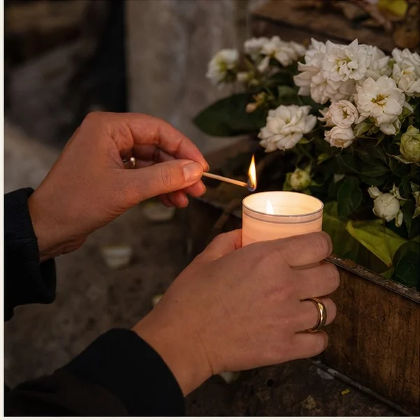 Small offerings and handwritten thanks beside candles